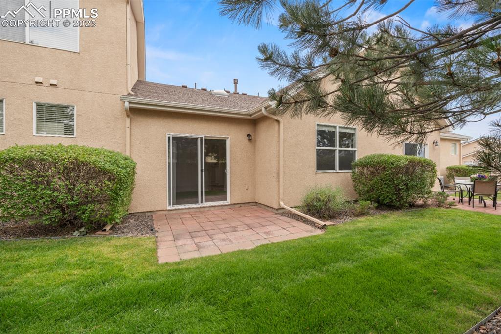 Image 22 of 22: Rear view of house featuring a patio, stucco siding, and a lawn