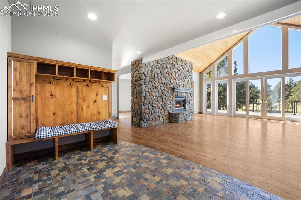 Image 19 of 50: Mudroom with high vaulted ceiling, a stone fireplace, dark wood finished fl