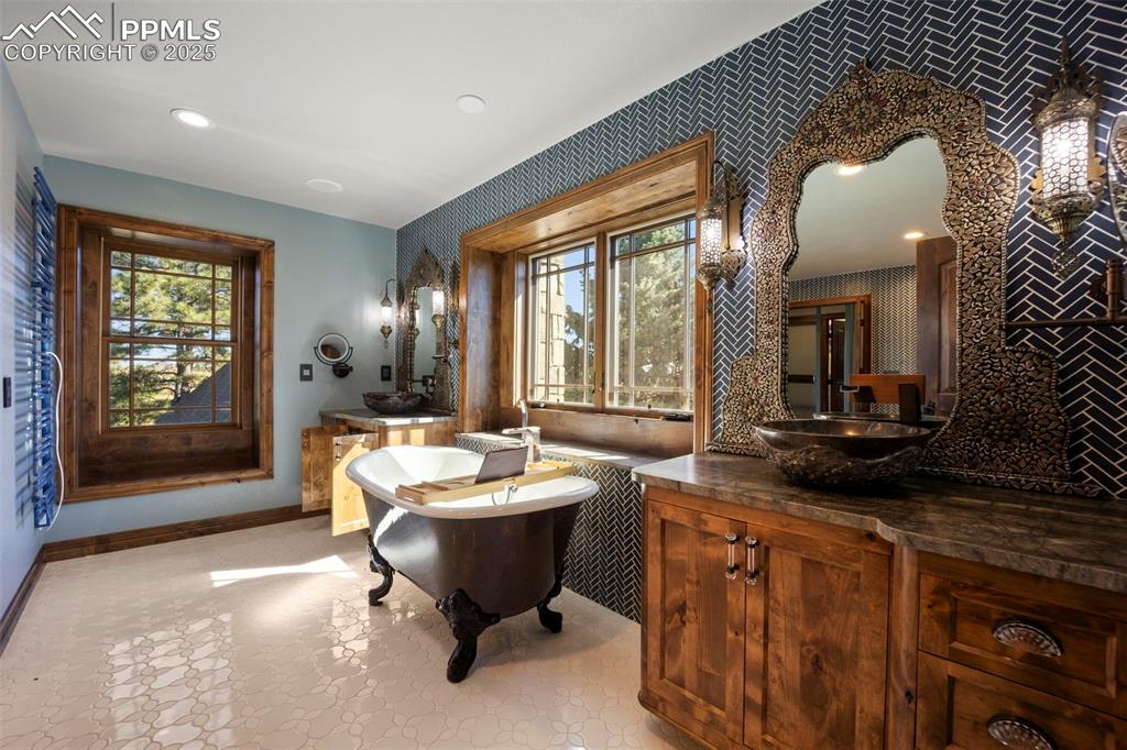 Image 23 of 50: Bathroom with a freestanding tub, vanity, recessed lighting, and wallpapere