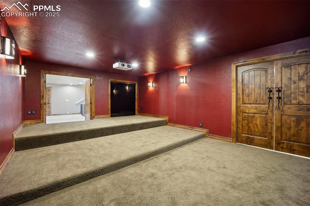 Image 33 of 50: Cinema room with a textured ceiling, a textured wall, and carpet floors
