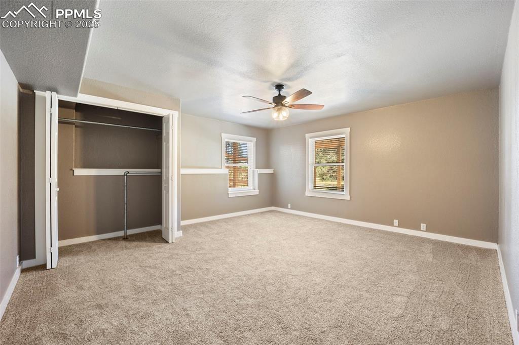 Image 35 of 50: Unfurnished bedroom featuring light carpet, a closet, ceiling fan, and a te