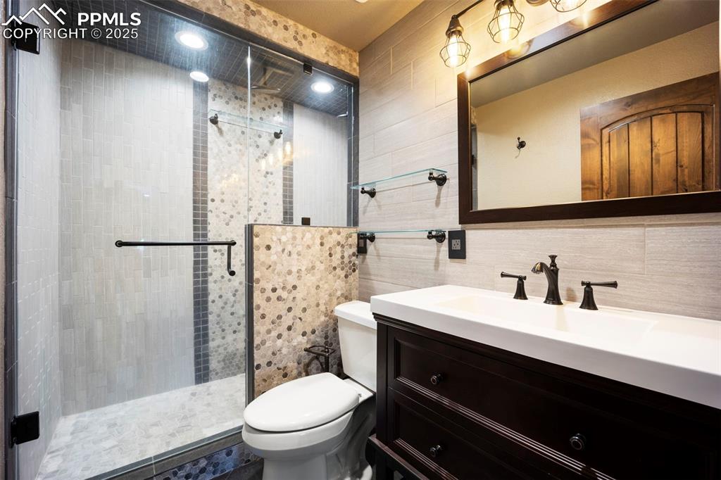 Image 36 of 50: Full bath featuring vanity, a shower stall, decorative backsplash, and tile