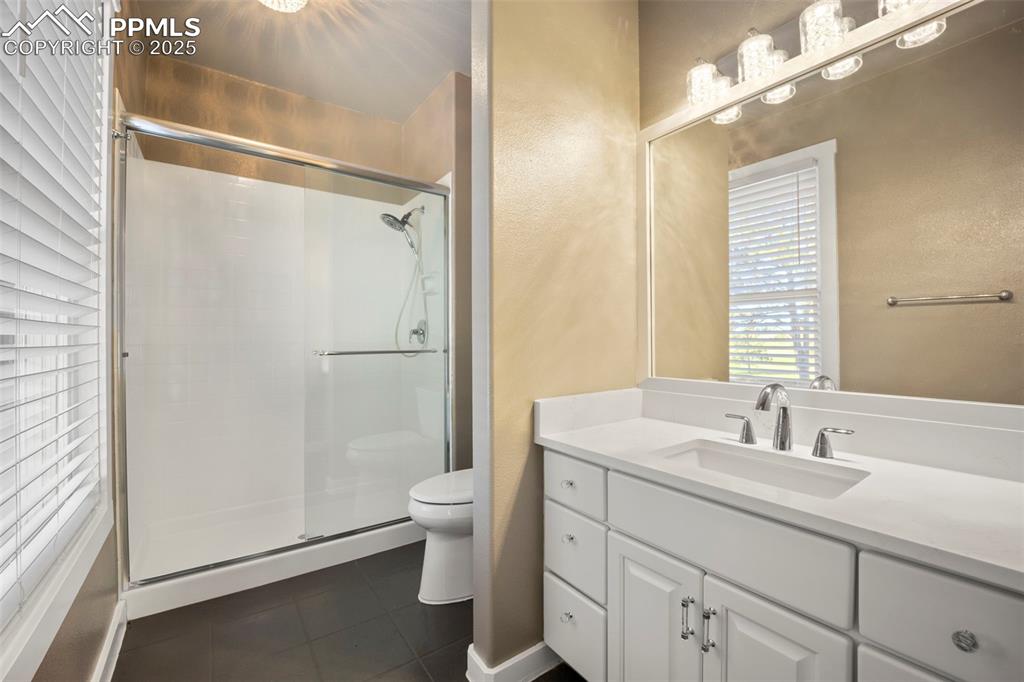 Image 43 of 50: Full bath featuring a stall shower, vanity, and dark tile patterned floorin