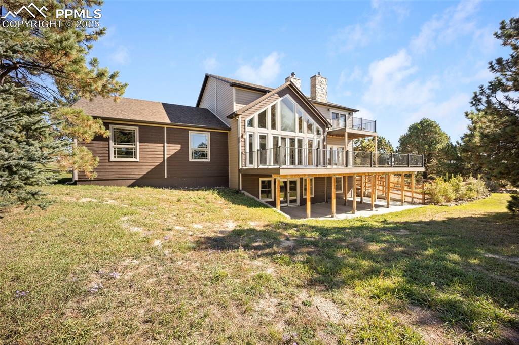 Image 45 of 50: Back of house with a yard, a patio area, a chimney, and a wooden deck