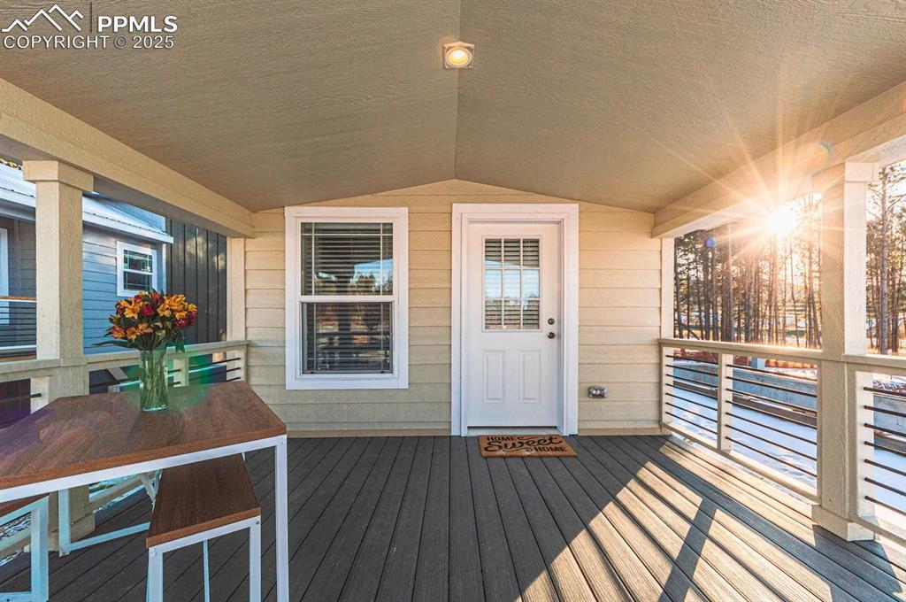 Image 25 of 26: Doorway to property featuring a wooden deck and outdoor dining area