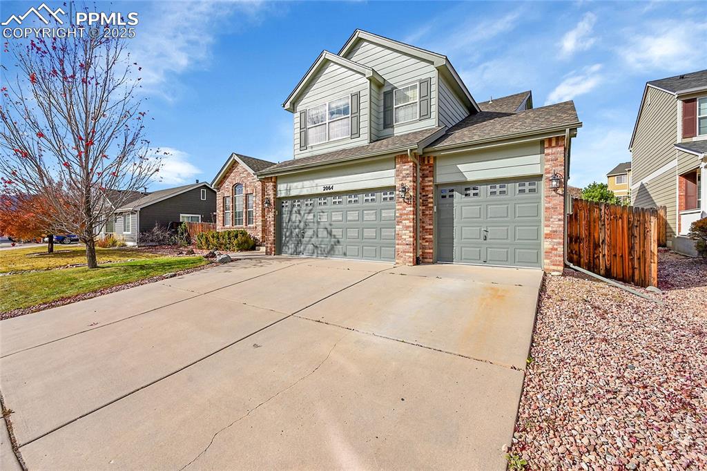 Caption: View of front of property featuring brick siding, concrete driveway, an attached garage, and roof wi