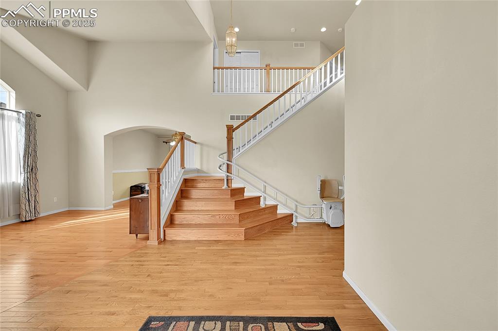 Image 3 of 44: Stairs featuring wood finished floors, a high ceiling, arched walkways, and