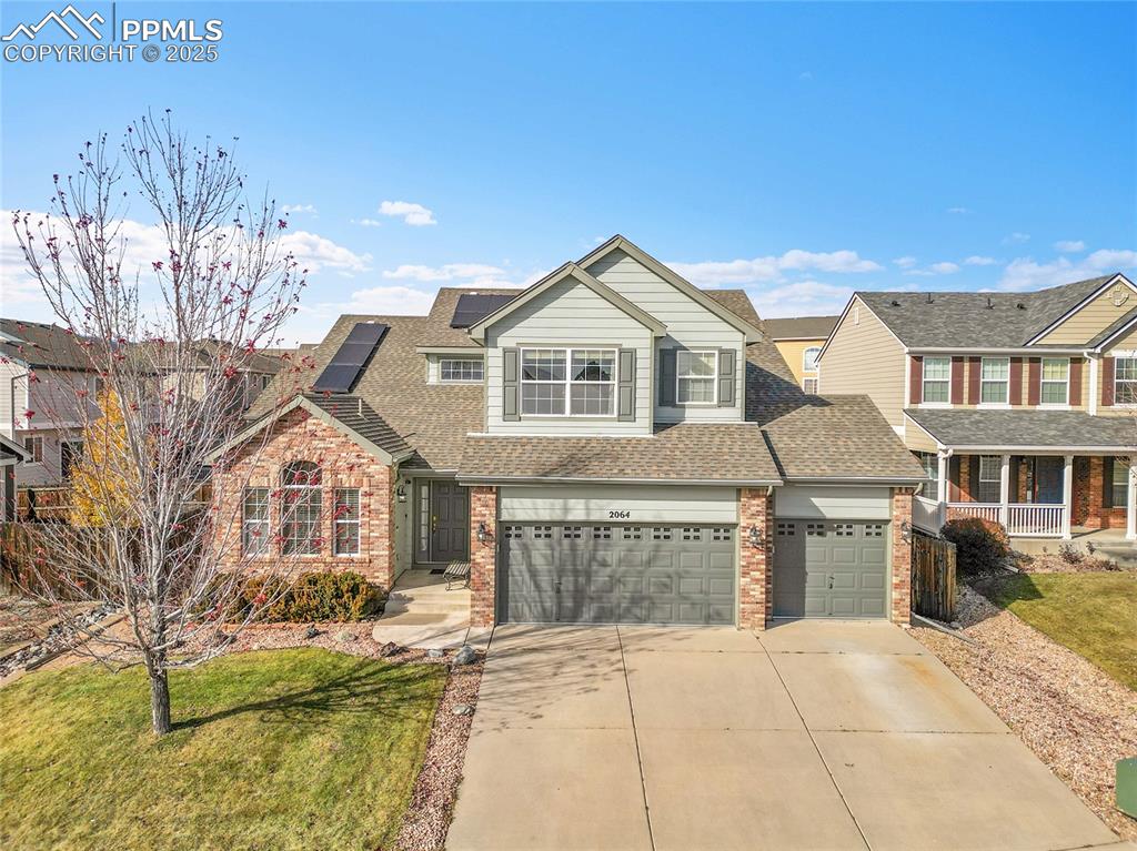 Image 35 of 44: Traditional home with roof with shingles, concrete driveway, brick siding, 