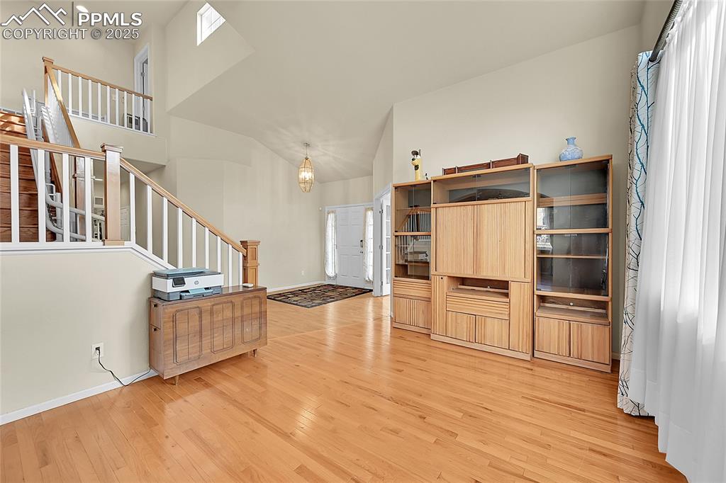 Image 7 of 44: Living room featuring stairs, a high ceiling, light wood-style floors, and 