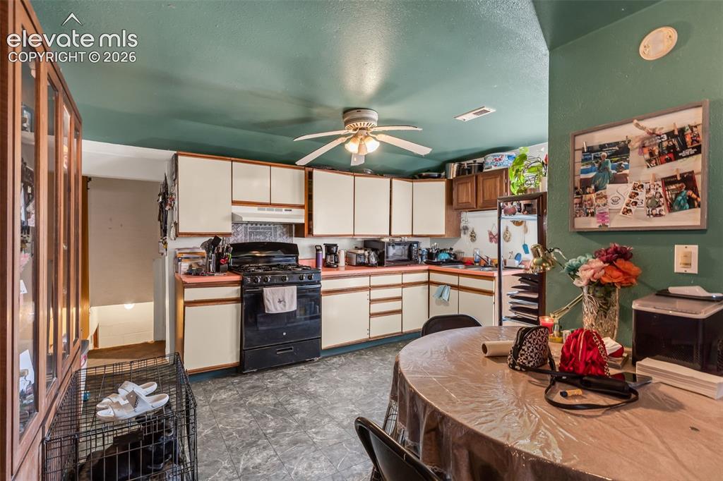 Image 10 of 29: L-shaped kitchen with white cabinetry and a built-in oven, featuring a ceil