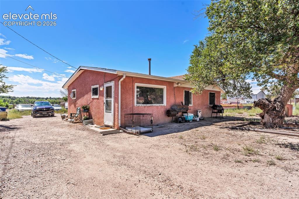 Image 19 of 29: Red stucco exterior with white trim, multiple windows, and a side entrance