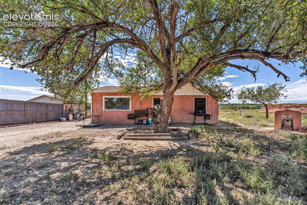 Image 28 of 29: Stucco exterior residence with a prominent mature tree providing natural sh