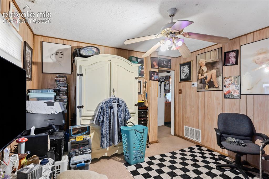 Image 3 of 29: Wall paneling, ceiling fan with integrated lighting, and carpeted flooring