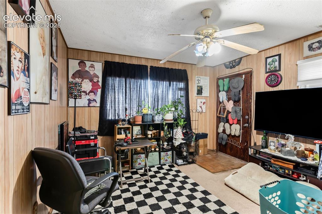 Image 4 of 29: Wood paneling on walls, ceiling fan with light fixture, window with dark dr