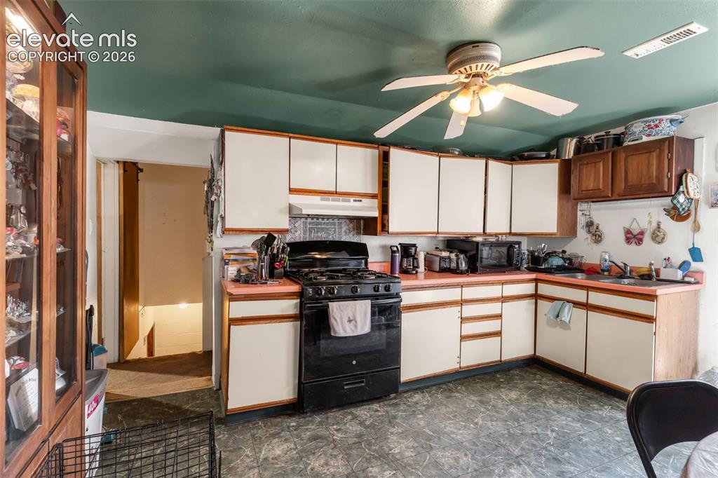 Image 9 of 29: Kitchen featuring L-shaped cabinetry, a built-in range, a single basin sink