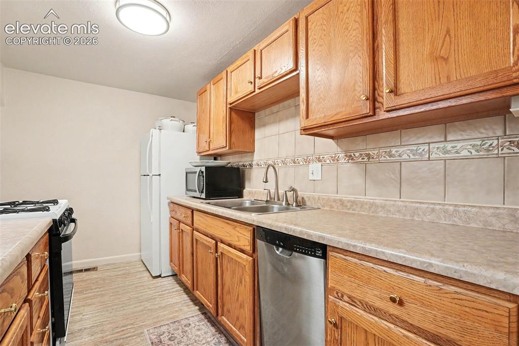 Image 6 of 24: Ceramic tile backsplash, oak cabinetry, and gas stove.