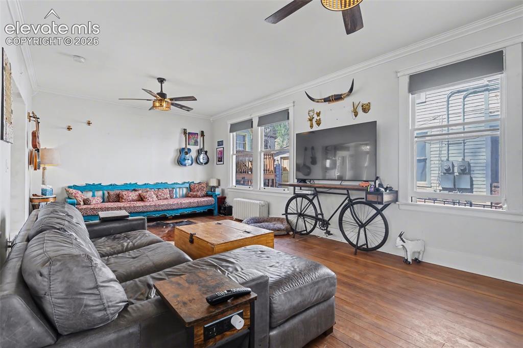 Image 14 of 43: Living / Dining area with ceiling fan, crown molding, hardwood, and large w