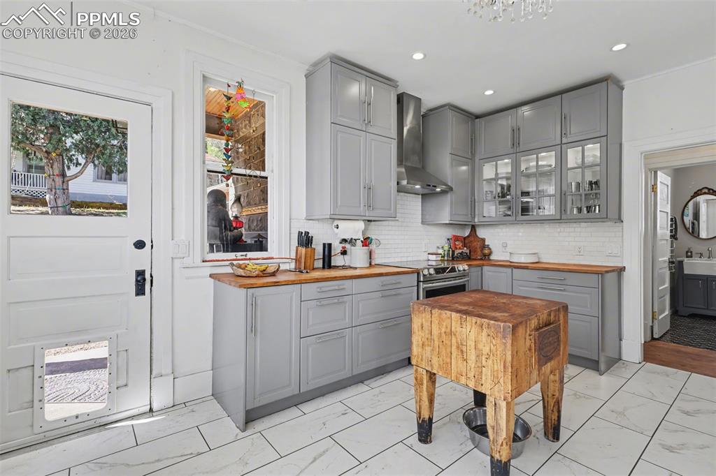 Image 17 of 46: Main house kitchen featuring gray cabinets, light tile, glass insert cabine