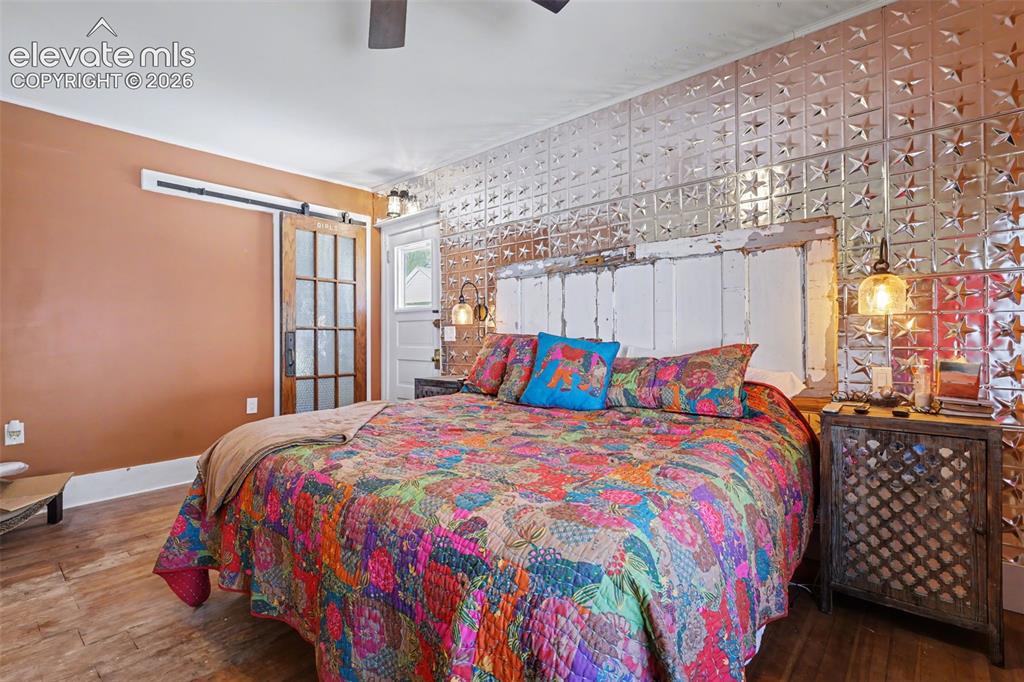 Image 20 of 43: Primary bedroom with hardwood flooring and barn door
