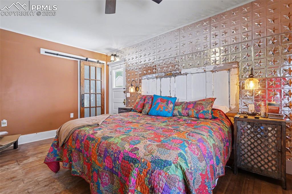 Image 23 of 46: Primary bedroom with hardwood flooring and barn door