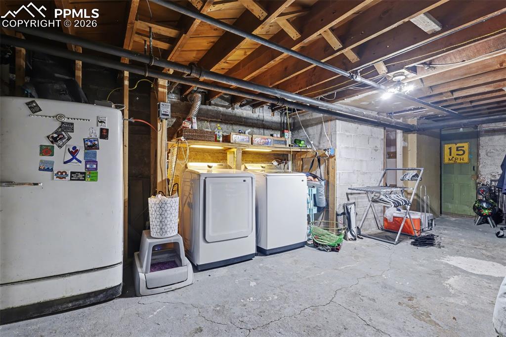 Image 34 of 46: Unfinished below grade area featuring freestanding refrigerator and washing