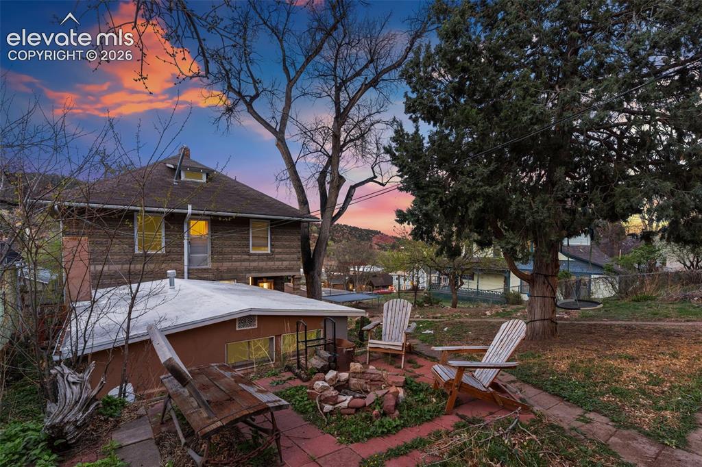 Image 6 of 43: Back of main home and studio cottage with an outdoor fire pit and a sitting