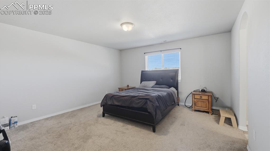 Image 17 of 36: Upper Level Primary Bedroom with neutral carpet, a walk in closet, and adjo
