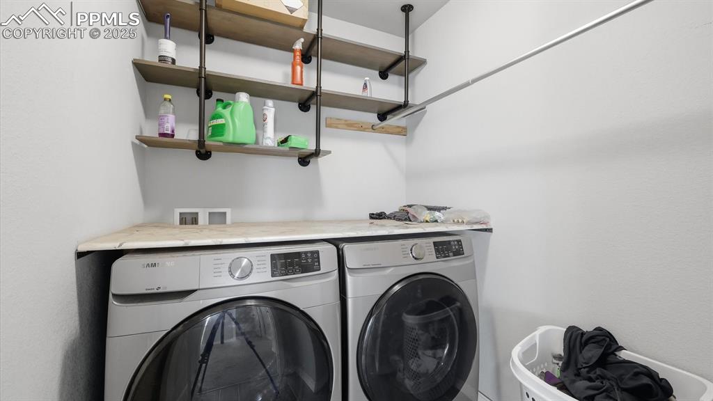 Image 27 of 36: The upper level Laundry Room has built in shelves and a washer and dryer th