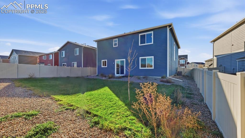 Image 30 of 36: Rear view of the home and backyard with vinyl fencing.