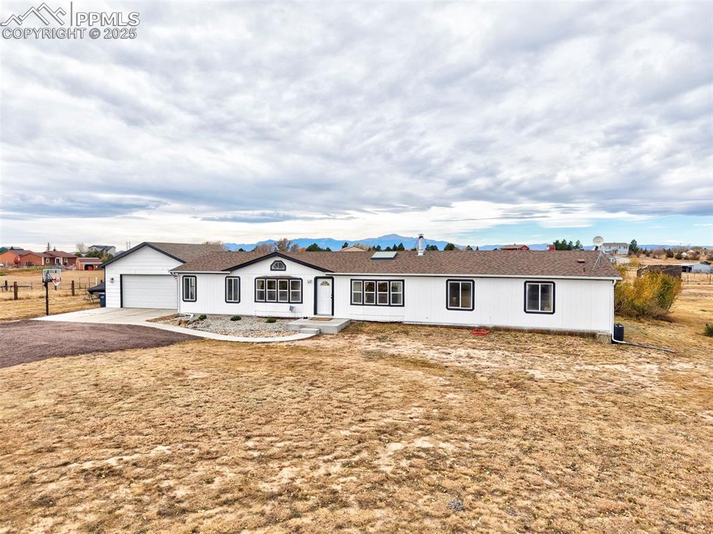 Caption: Single story home featuring a garage, driveway, and roof with shingles