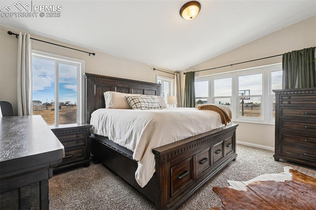 Image 10 of 31: Bedroom with light colored carpet and vaulted ceiling