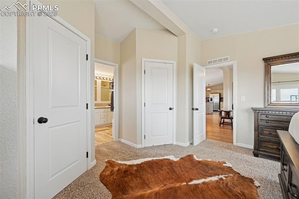 Image 11 of 31: Bedroom with light colored carpet, connected bathroom, stainless steel frid