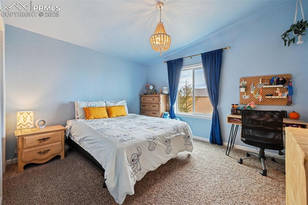 Image 19 of 31: Bedroom featuring carpet floors, vaulted ceiling, an office area, a chandel