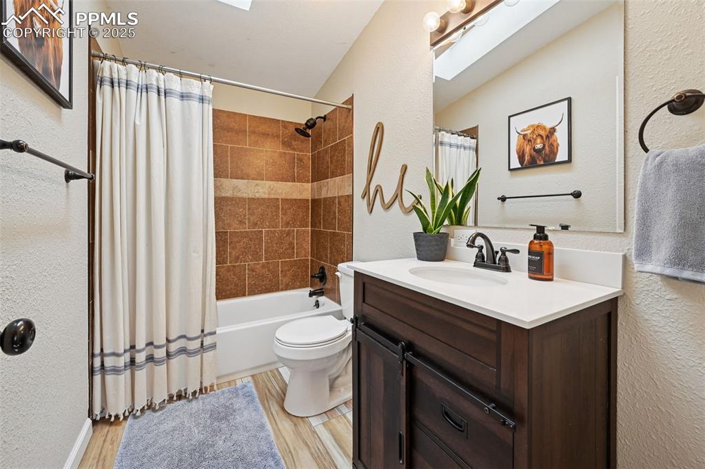 Image 21 of 31: Bathroom featuring a textured wall, a skylight, shower / bath combination w