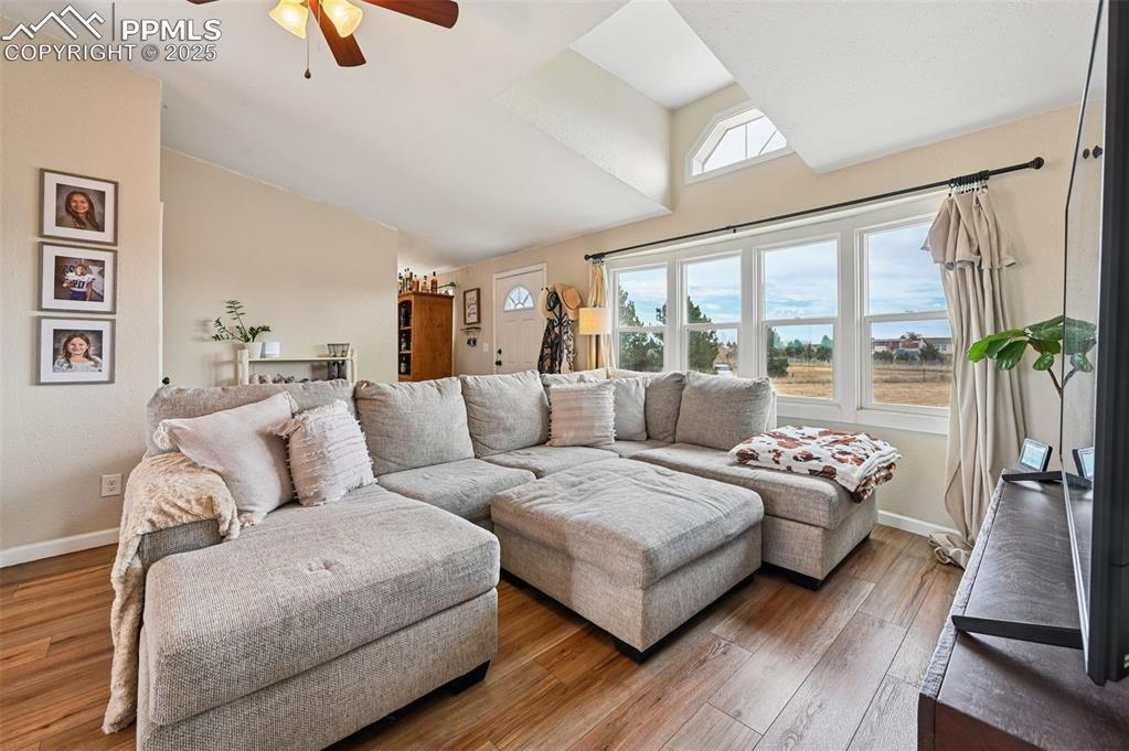 Image 4 of 31: Living room with ceiling fan, wood finished floors, and high vaulted ceilin
