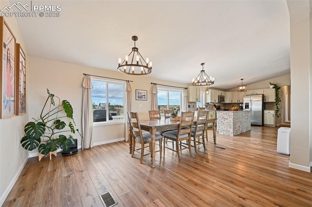 Image 5 of 31: Dining space with light wood-type flooring, a chandelier, and lofted ceilin