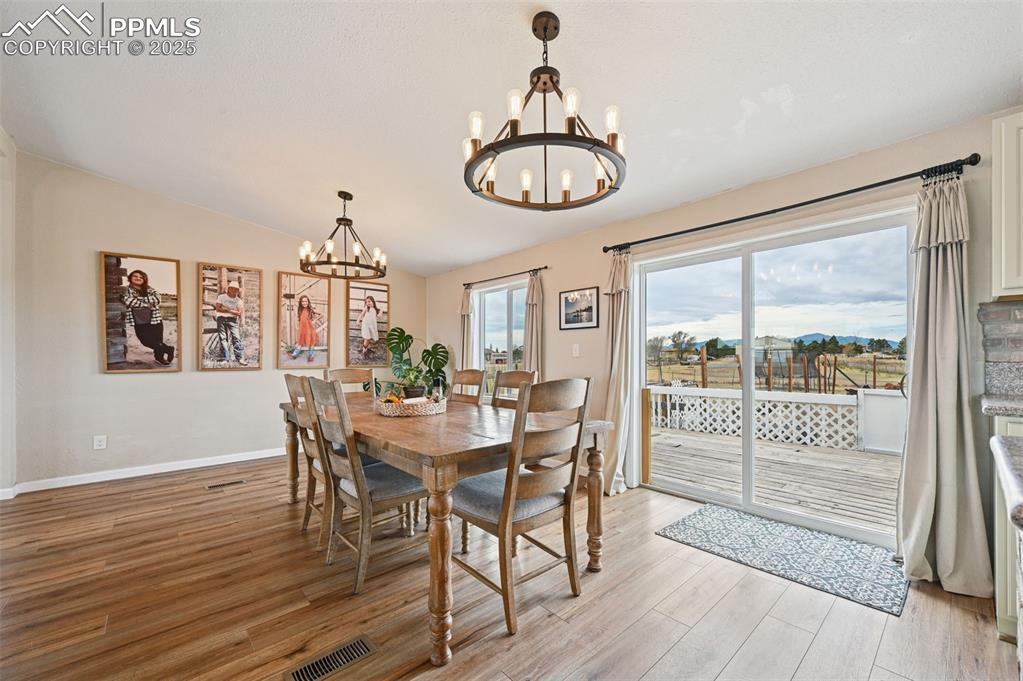 Image 6 of 31: Dining space featuring light wood-style flooring, vaulted ceiling, and a ch