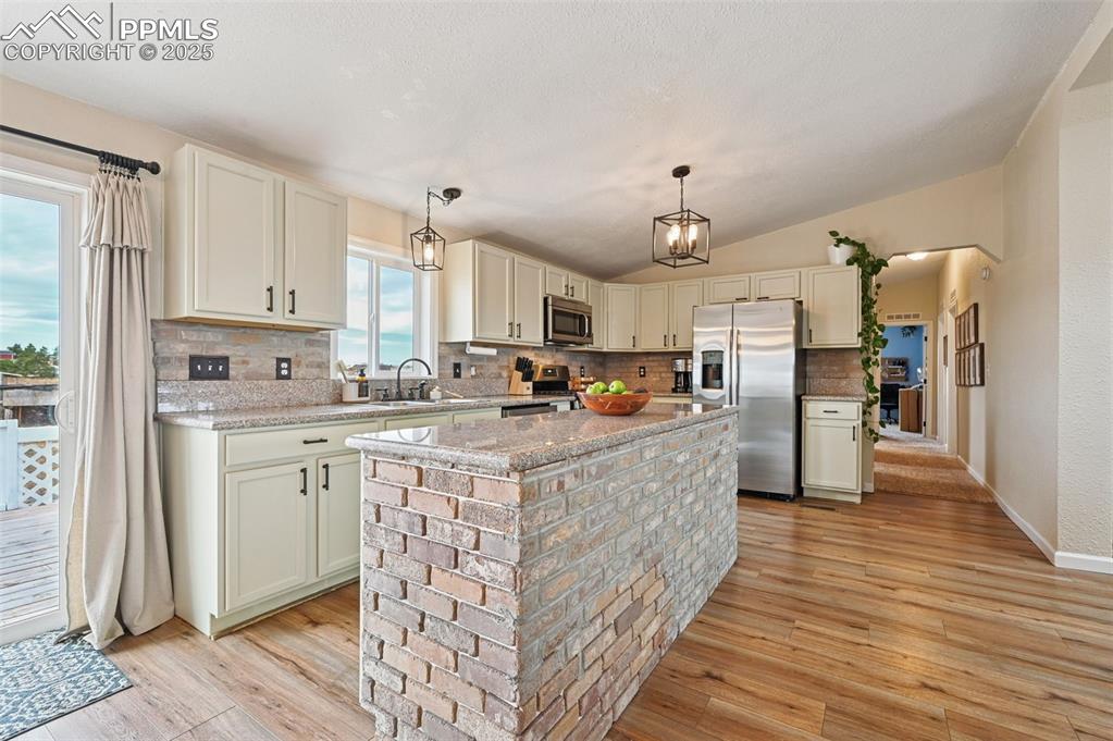 Image 7 of 31: Kitchen with decorative backsplash, stainless steel appliances, light wood-