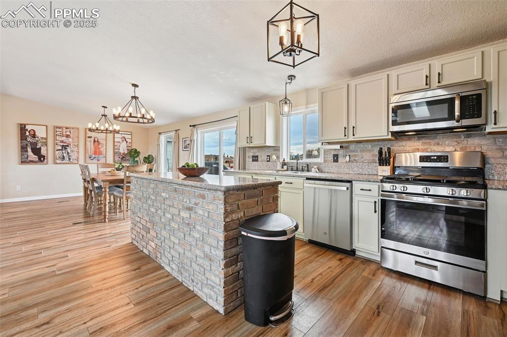 Image 8 of 31: Kitchen with a chandelier, pendant lighting, appliances with stainless stee
