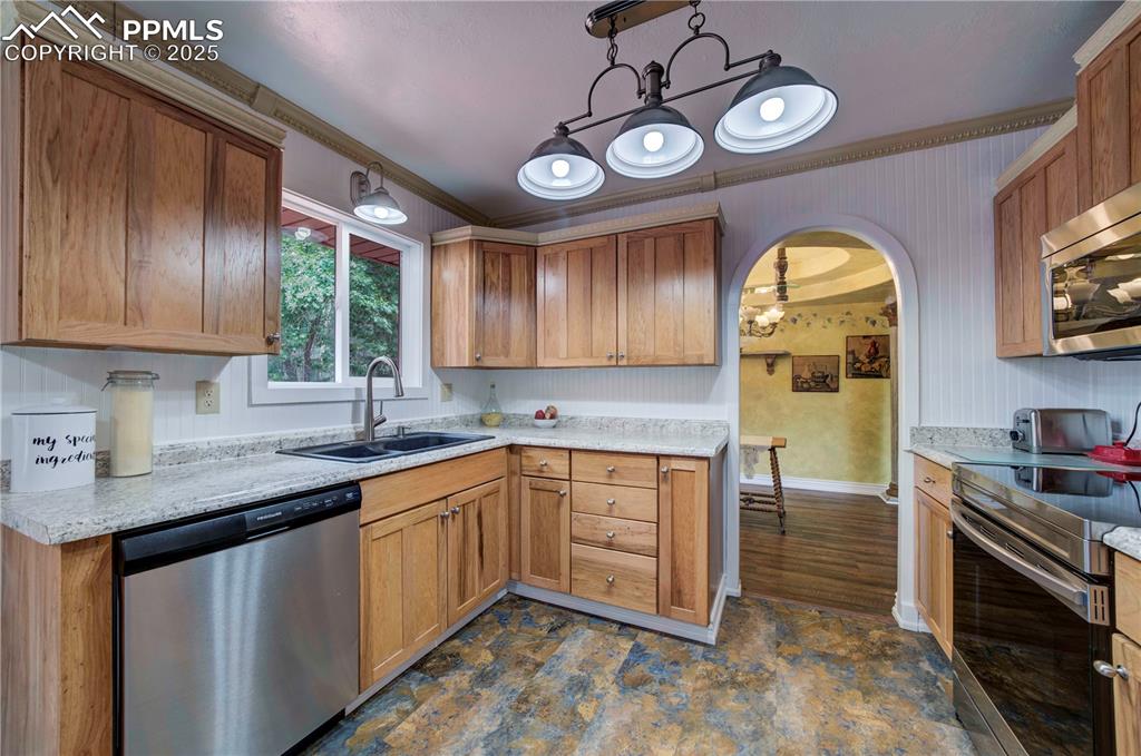 Image 10 of 50: Kitchen with appliances with stainless steel finishes, crown molding, arche
