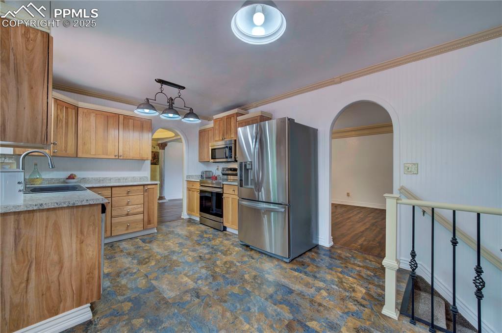 Image 12 of 50: Kitchen featuring arched walkways, light countertops, stainless steel appli
