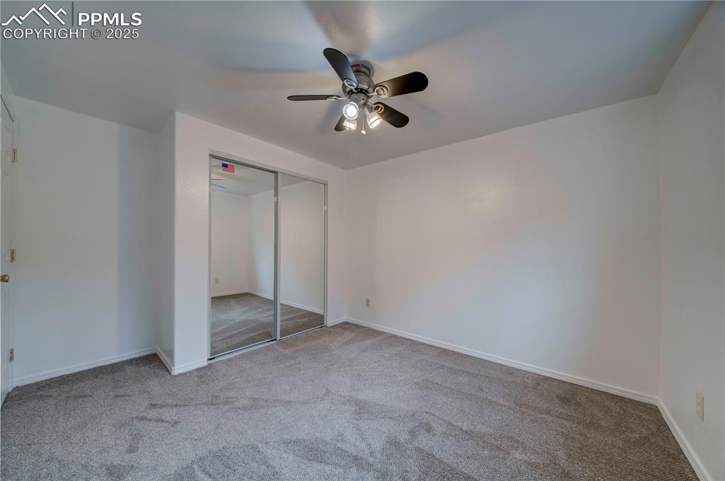 Image 22 of 50: Unfurnished bedroom featuring light carpet, a closet, and a ceiling fan
