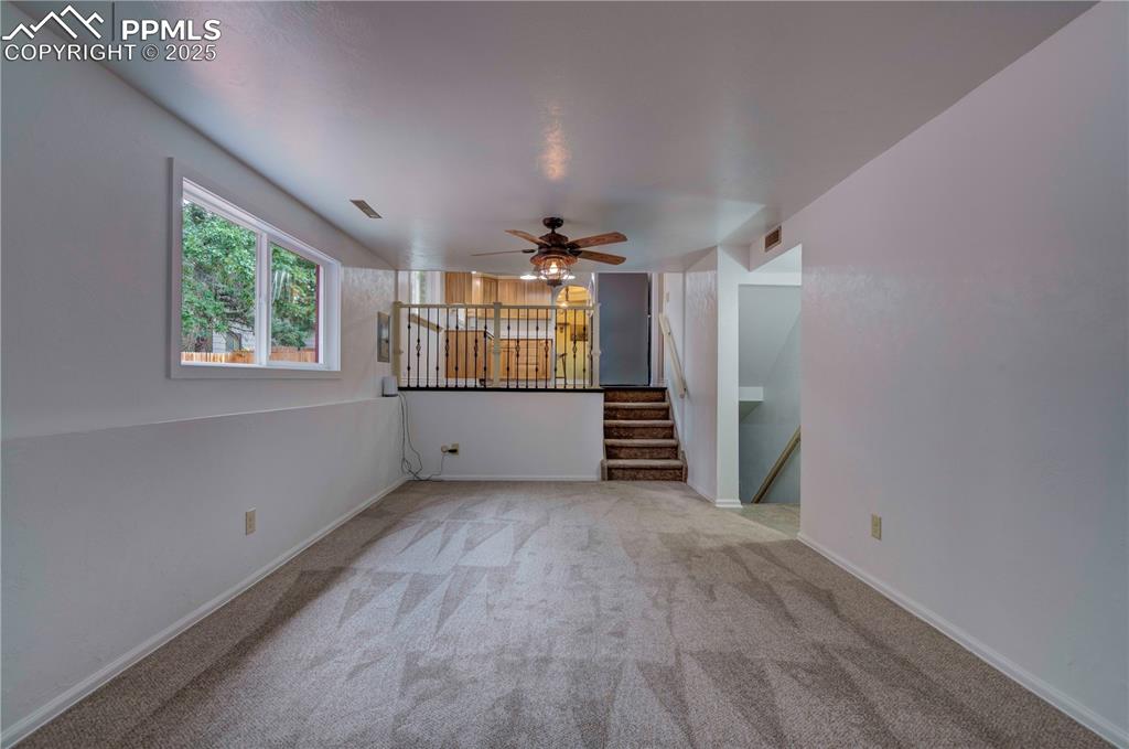 Image 24 of 50: Unfurnished living room featuring light colored carpet, ceiling fan, and st