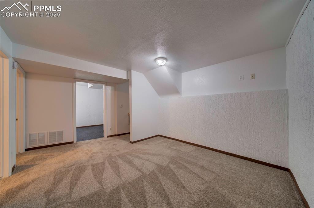 Image 29 of 50: Additional living space featuring a textured ceiling, a textured wall, carp