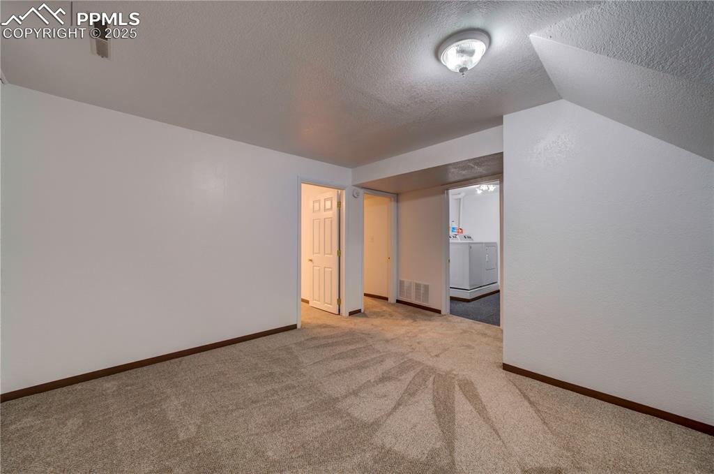Image 30 of 50: Bonus room with a textured ceiling and light colored carpet