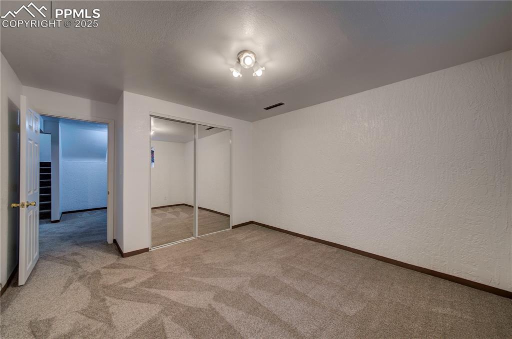Image 31 of 50: Unfurnished bedroom with light carpet, a textured wall, a textured ceiling,