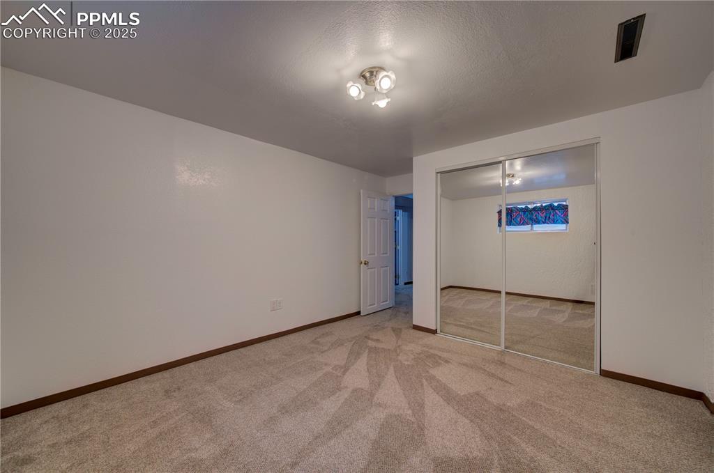 Image 32 of 50: Unfurnished bedroom featuring light colored carpet, a closet, and a texture