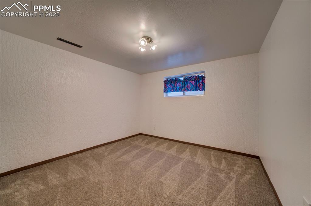 Image 33 of 50: Empty room with a textured wall, a textured ceiling, and carpet floors