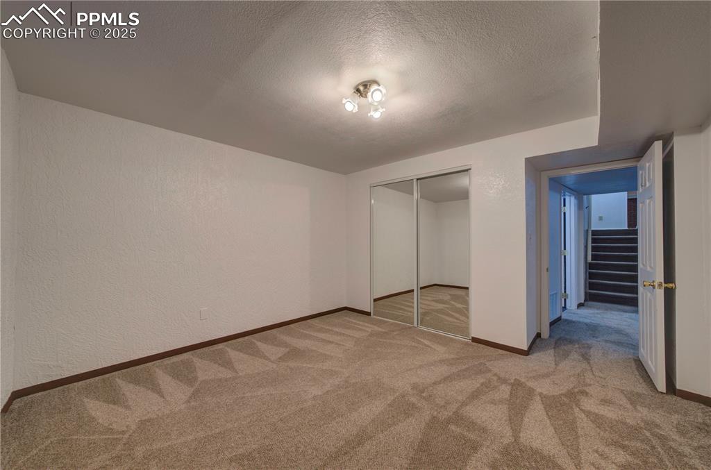 Image 34 of 50: Unfurnished bedroom with light colored carpet, a closet, a textured ceiling
