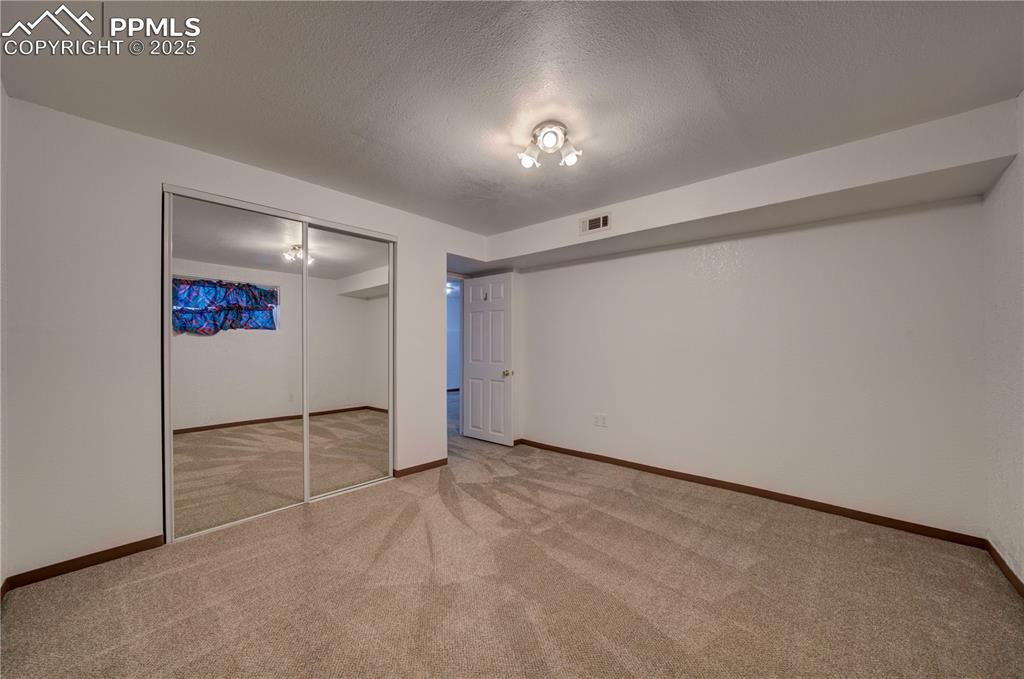 Image 35 of 50: Unfurnished bedroom with carpet, a textured ceiling, and a closet